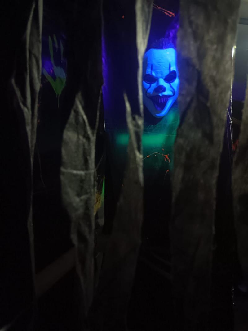 Máscara de payaso entre cortinas con luz azul